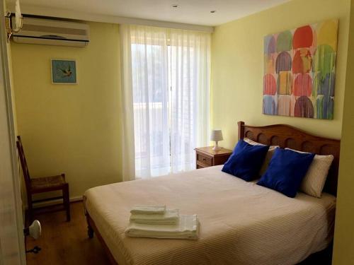 - une chambre avec un lit doté d'oreillers bleus et d'une fenêtre dans l'établissement Sea and Pinewood Ofir Apartment, à Fão