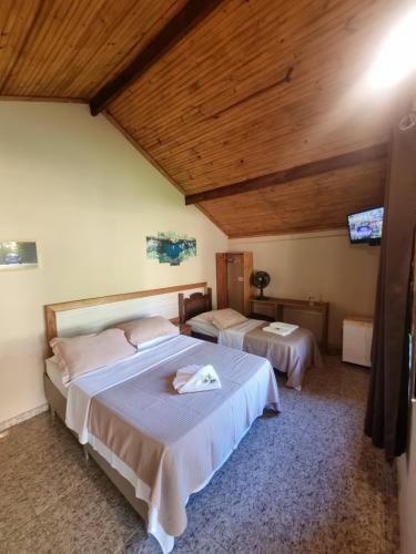 Chalés Encantos da Serra في كارانكاس: غرفة نوم بسريرين وسقف خشبي