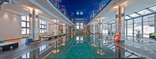 a large swimming pool in a building with windows at Grand Nosalowy Dwór in Zakopane