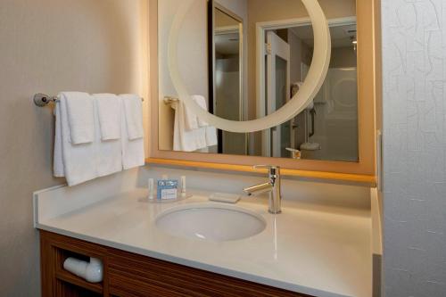 een badkamer met een wastafel met een spiegel en handdoeken bij SpringHill Suites St. Louis Brentwood in Brentwood