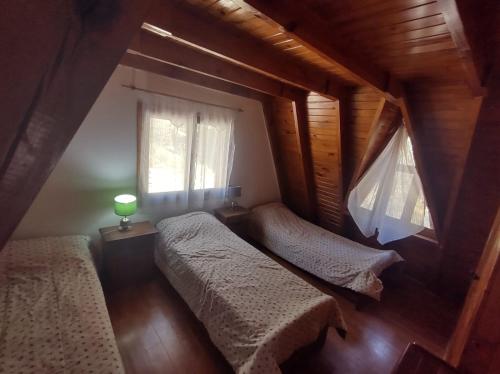 1 dormitorio en el ático con 2 camas y ventana en Bungalow Villa Pehuenia en Villa Pehuenia