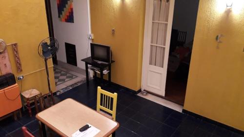 Habitación con mesa, TV y puerta. en Bienvenidos al Sur en Buenos Aires