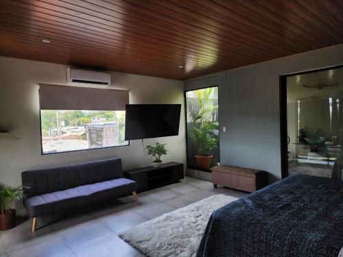 a bedroom with a bed and a flat screen tv at Los Portones de Ataco in Concepción de Ataco