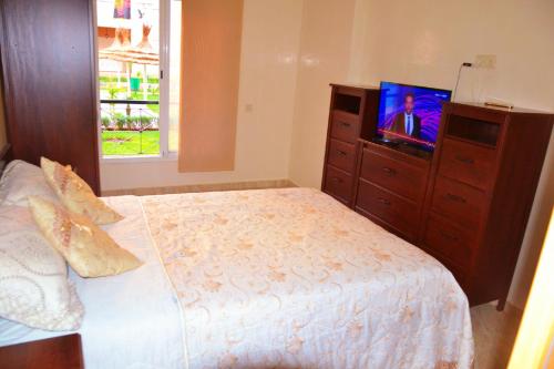 a bedroom with a bed and a dresser with a television at Reco flores PALM in Ben Slimane