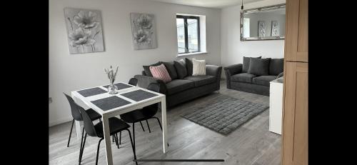 a living room with a table and a couch at 2bed luxury modern apartment in Swansea
