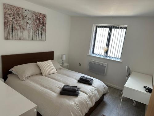 a bedroom with a bed with two black towels on it at 2bed luxury modern apartment in Swansea