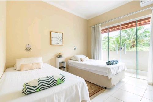Duas camas num quarto com uma janela em Linda casa com piscina aquecida e ar condicionado a 1h do RJ em Guapimirim