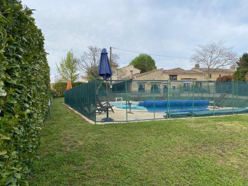 - une piscine avec une clôture et un parasol bleu dans l'établissement Gîte 3 étoiles avec piscine Dordogne, à Minzac