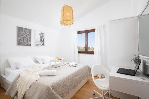 a white bedroom with a bed and a desk at Cesare Apartment, with Swimming pool and Sea view in Ližnjan