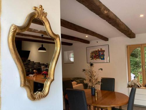 une salle à manger avec un grand miroir doré sur le mur dans l'établissement Maison avec jardin /proche plage, à Planguenoual