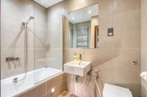 Modern 2 bedrooms 2bathrooms behind Nobu hotel في لندن: حمام مع حوض وحوض ومرآة
