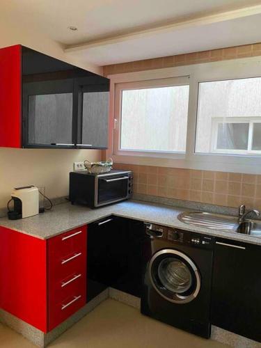 a kitchen with a washing machine and a microwave at appartement neuf ensoleillé avec parking sous sol in Agadir