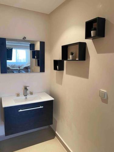 La salle de bains est pourvue d'un lavabo et d'un miroir. dans l'établissement appartement neuf ensoleillé avec parking sous sol, à Agadir