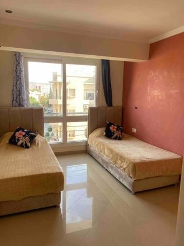- une chambre avec 2 lits et une grande fenêtre dans l'établissement appartement neuf ensoleillé avec parking sous sol, à Agadir