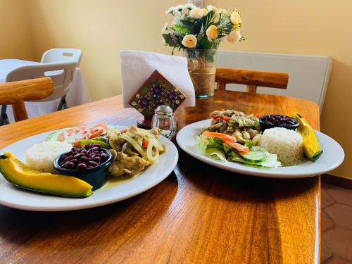 two plates of food on a wooden table at Hotel y Restaurante Virgen de Fátima in La Ceiba