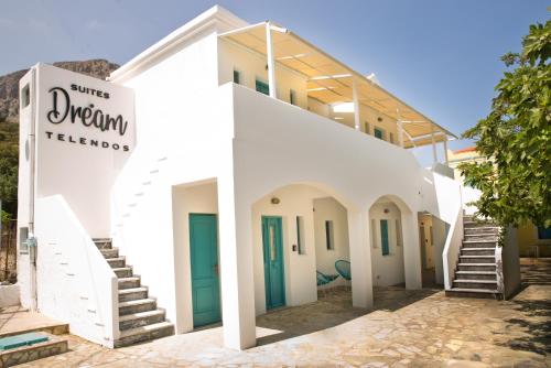 - un bâtiment blanc avec des portes et des escaliers bleus dans l'établissement SUITES DREAM TELENDOS, à Telendos