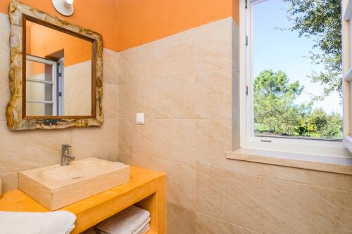 W łazience znajduje się umywalka i lustro. w obiekcie Gotas de Luar Turismo Rural w mieście Vila Nova de Milfontes