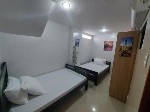 two beds in a small room with white walls at Ma Garbo Hotspring Private Resort in Calamba