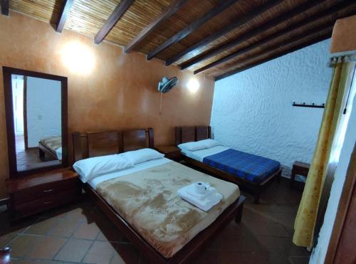 a bedroom with two beds and a mirror in it at CABAÑAS VILLA EMILY in Curití