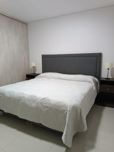 1 dormitorio con 1 cama blanca grande y 2 mesitas de noche en Departamento San Juan - Capital en San Juan