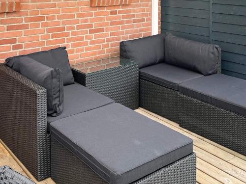 two wicker chairs and a bench on a patio at 10 person holiday home in Roslev in Flovtrup