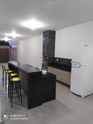 a kitchen with a black counter and yellow bar stools at Área de Lazer Santa Rita in Delfinópolis