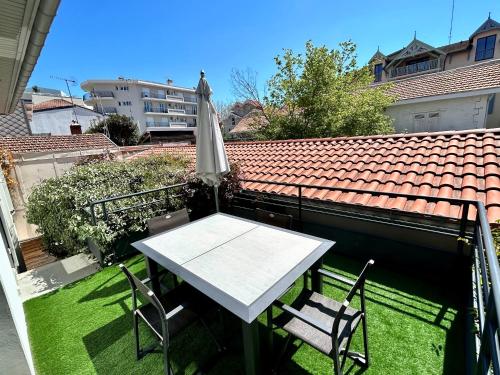 a table and chairs on a balcony with an umbrella at Villa Centre ville in Arcachon