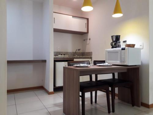 eine Küche mit einem Tisch mit Stühlen und einer Mikrowelle in der Unterkunft Flat Completo no Soho Promenade - Wi-Fi e NF in Campos dos Goytacazes