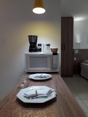 a table with plates and utensils and a blender at Flat Completo no Soho - Wi-Fi e NF in Campos dos Goytacazes