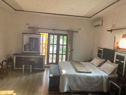 a bedroom with a bed and a dresser and a mirror at Serene & quiet 2- Bedroom Cottage Statelodge area in Shimwansa