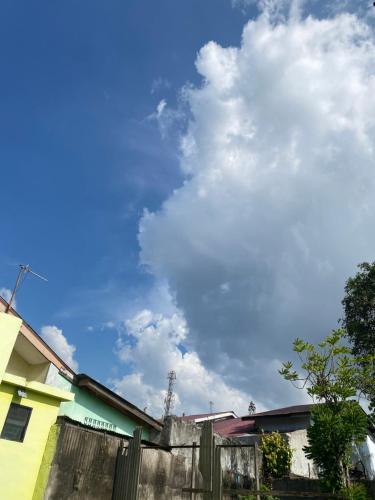 een blauwe lucht met wolken boven een hek bij House Edan in Medan