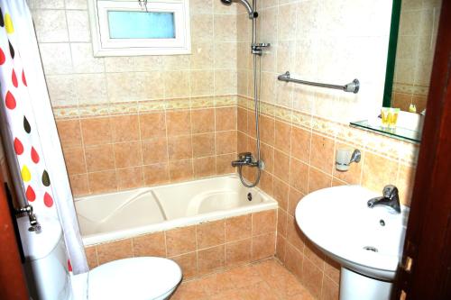 a bathroom with a tub and a sink and a toilet at Arinza Tower Quality Apartments in Kuwait