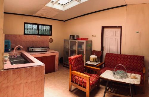 eine Küche mit einem Waschbecken, einem Sofa und einem Tisch in der Unterkunft Taratak Homestay in Bukittinggi