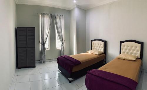 sypialnia z 2 łóżkami i oknem w obiekcie Mandi Angin "Syariah" Homestay w mieście Bukittinggi