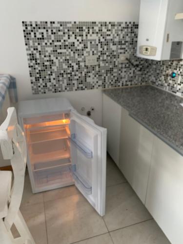 a small kitchen with an open refrigerator in the corner at Depto Caleta Madryn in Puerto Madryn