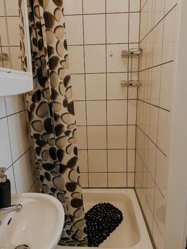 a bathroom with a sink and a shower with a black rug at Unser sonniges Apartment mit WLAN, Netflix, XBox in Magdeburg