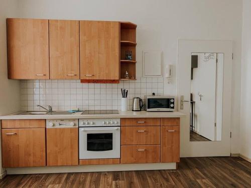 a kitchen with wooden cabinets and a microwave at Unser sonniges Apartment mit WLAN, Netflix, XBox in Magdeburg