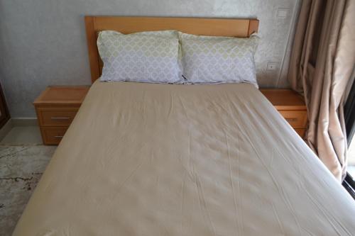 Appartement très bien meublé - Résidence sécurisée في أغادير: سرير مع اللوح الأمامي الخشبي والوسائد عليه
