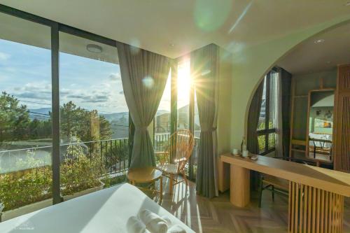 a bedroom with a bed and a desk and a balcony at La Villa Da Lat in Khu Chi Lăng