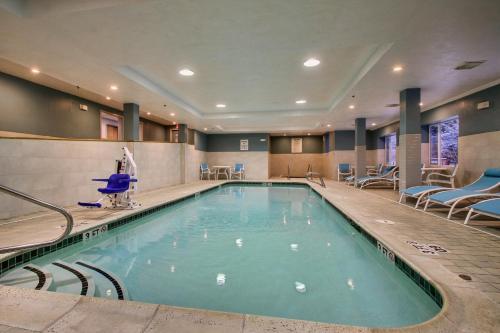 a swimming pool in a hotel with chairs and tables at Holiday Inn Express & Suites - Lincoln East - White Mountains by IHG in Lincoln