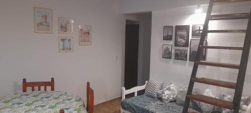 1 dormitorio con escalera, cama y cuadros en la pared en Dept. Miramar (1 cuadra del mar y 3 de SanBer.) en Costa Azul