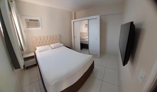 Apartamento BEIRA-MAR com 2 quartos في ماسيو: غرفة نوم بيضاء صغيرة مع سرير ومرآة
