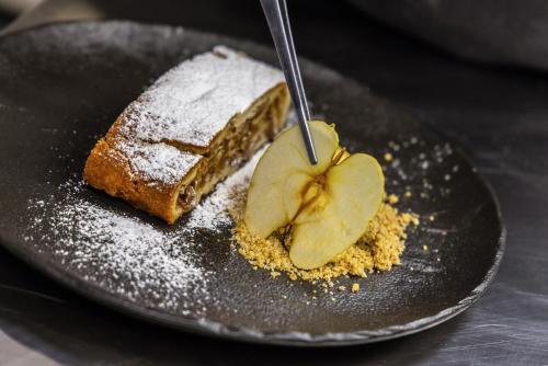 a piece of cake on a black plate with a dessert at Garden Wellness Hotel S in Andalo
