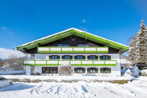 a building with a green roof in the snow at Landhaus am Stein in Bad Wiessee