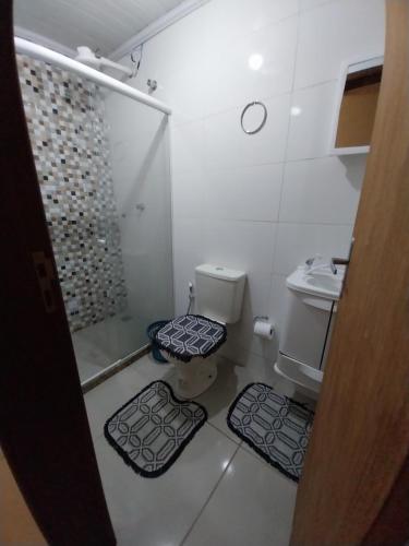 a bathroom with a toilet and a shower and two mats at Casa 4 in Campos dos Goytacazes