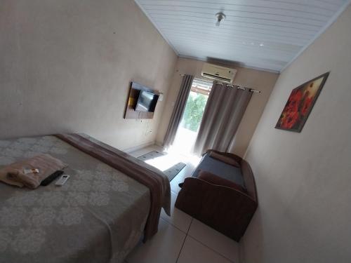 a bedroom with a bed and a television and a window at Casa 4 in Campos dos Goytacazes