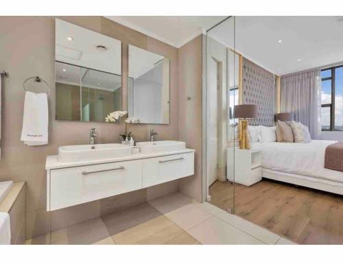 uma casa de banho com um lavatório, uma cama e um espelho. em Masingita Towers, 15 West Road South Road em Joanesburgo
