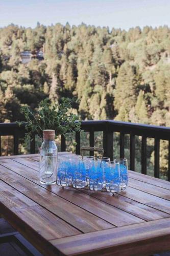 a wooden table with blue glasses on a wooden table at @wild_olive_den ~ Serene Weekend Getaway Cabin in Running Springs