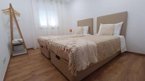 a bedroom with two beds with white walls and wood floors at Mondalva Apartamentos in São Pedro de Alva
