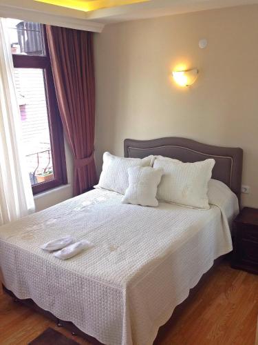 a bedroom with a bed with white sheets and a window at Naz Wooden House Inn in Istanbul